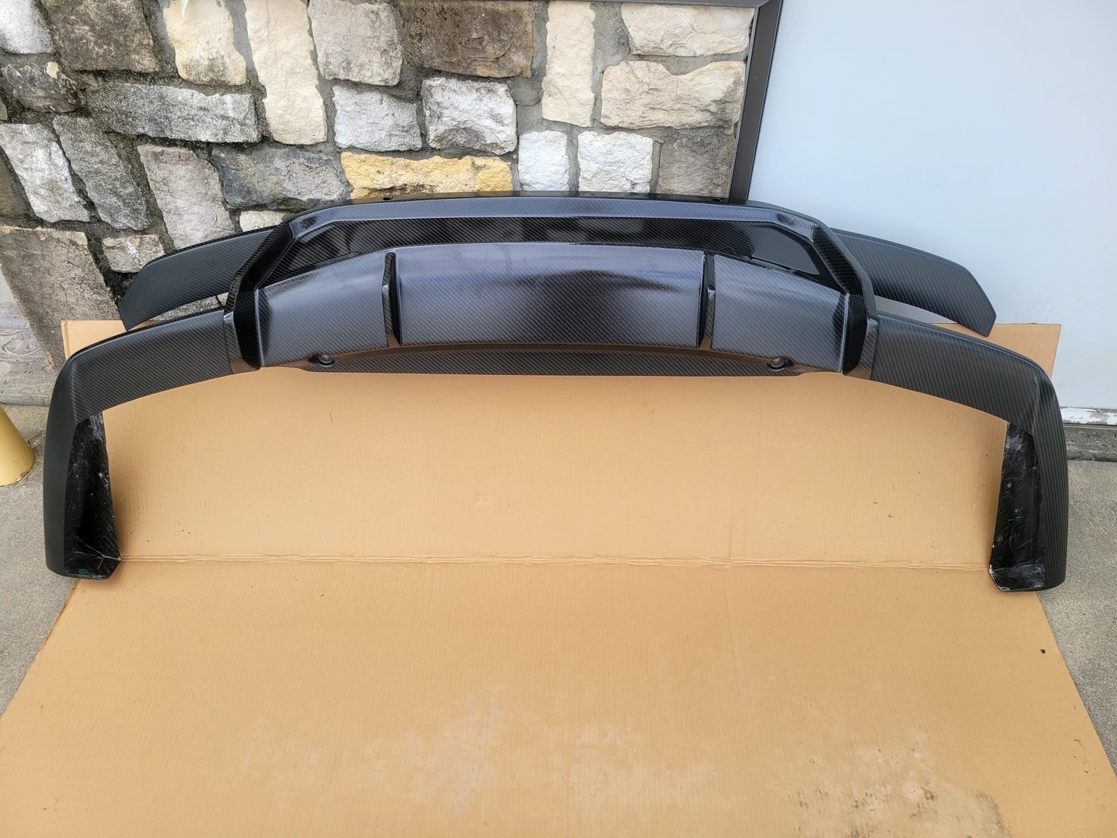 BMW X6 carbon fiber rear diffuser with yellowed, aged epoxy finish before refinish