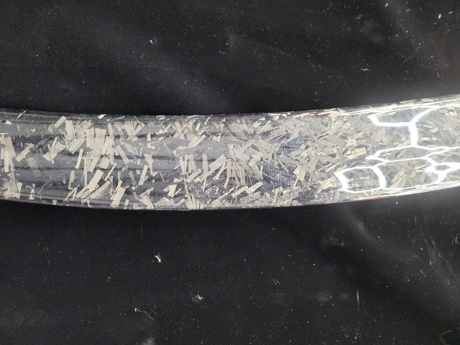 Close-up of forged carbon fiber chopped-fiber pattern under gloss clear coat