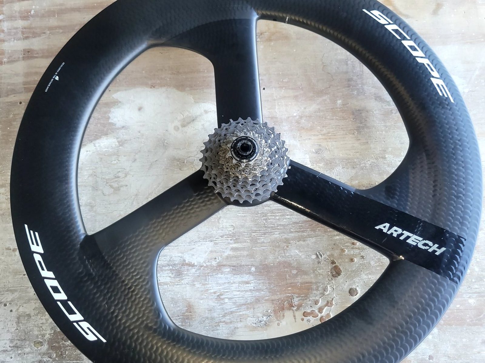 Repaired carbon fiber trispoke triathlon wheel, rear view with cassette